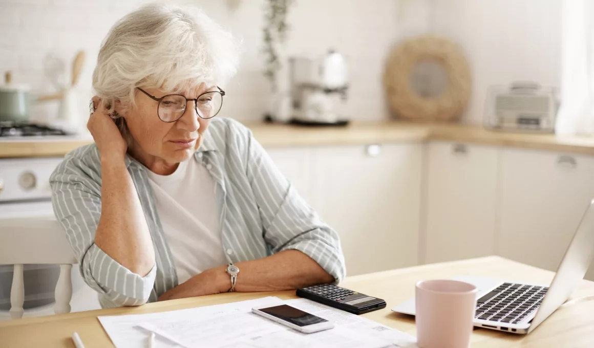 Femme âgée préoccupée par finances à domicile.