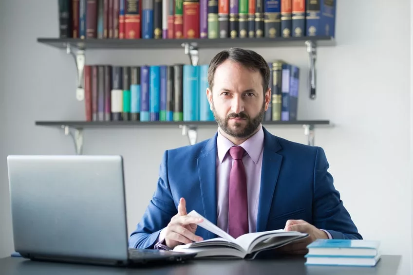 Homme en costume avec livre et ordinateur