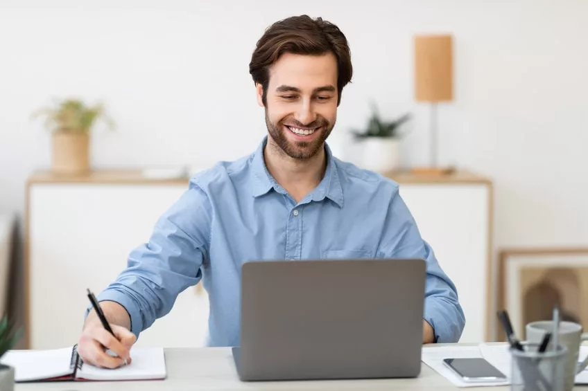 Homme souriant travaillant sur ordinateur portable