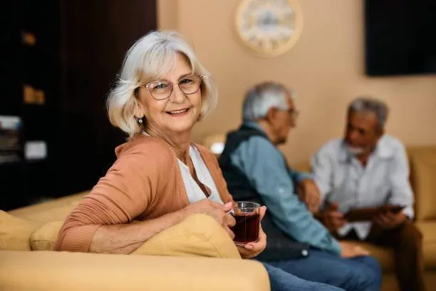 Femme âgée souriante avec une tasse de thé.