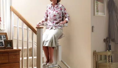 Femme sur siège monte-escalier intérieur.