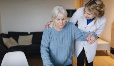 Aide soignante soutenant une femme âgée