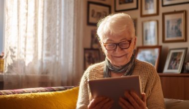 Personne âgée souriant en regardant une tablette.