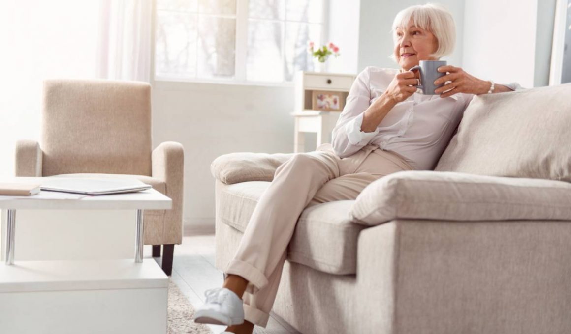 Femme âgée assise, buvant une tasse de thé.