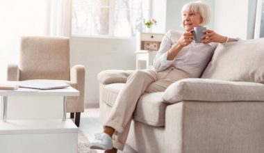 Femme âgée assise, buvant une tasse de thé.