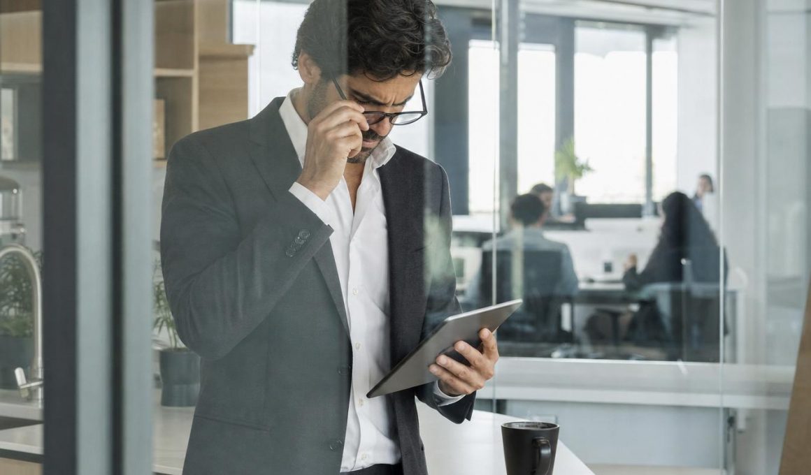 Homme en costume consultant une tablette au bureau