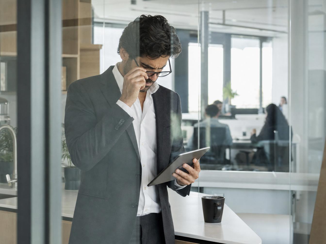 Homme en costume consultant une tablette au bureau