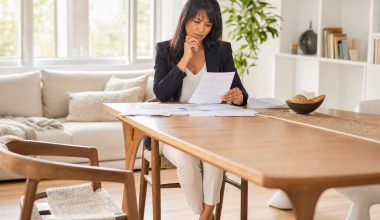 Femme dans la quarantaine consultant ses documents de retraite dans un appartement lumineux