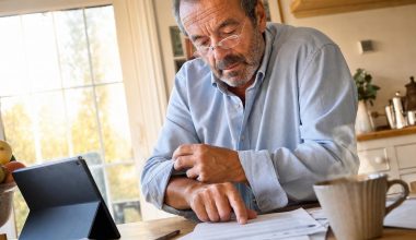 Homme senior examinant des factures à table